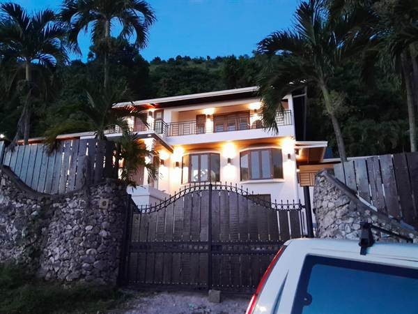 Smart villa gated entrance with exterior lighting at dusk in Jacks Hill, Kingston