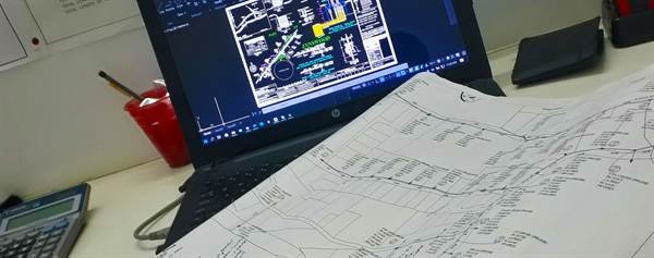 AutoCAD pole line design drawing on laptop with hand-marked map